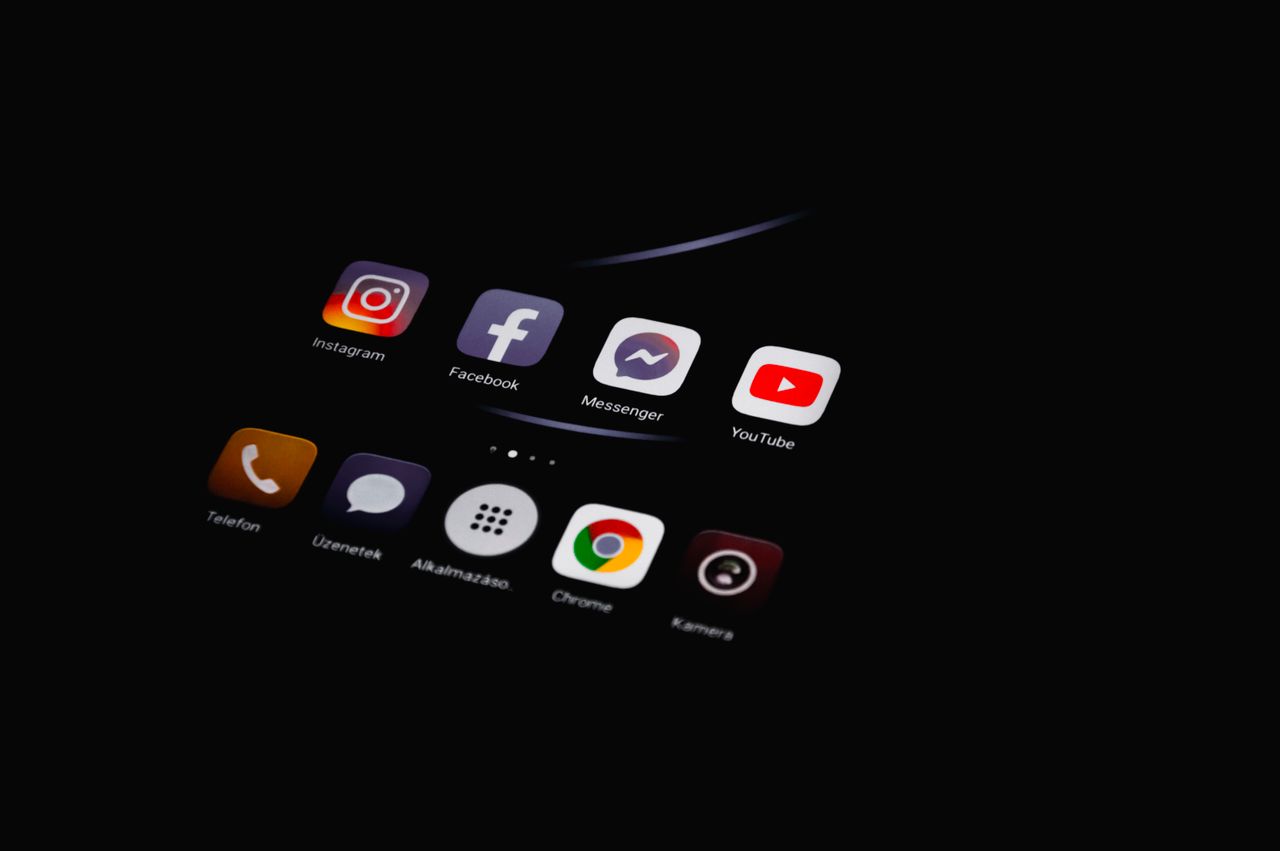 about-us-02 Close-up of smartphone displaying popular social media apps in dim lighting.
